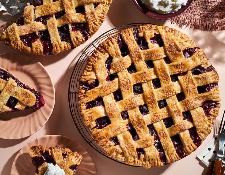 Blueberry lattice pie with plates of pie slices