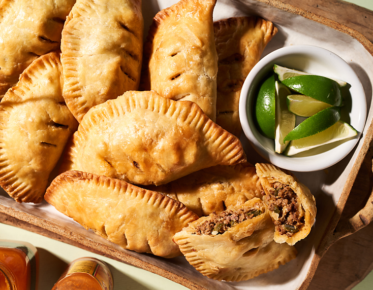 Beef and cheese empanadas with small bowl of lime slices Beef and cheese empanadas with small bowl of lime slices