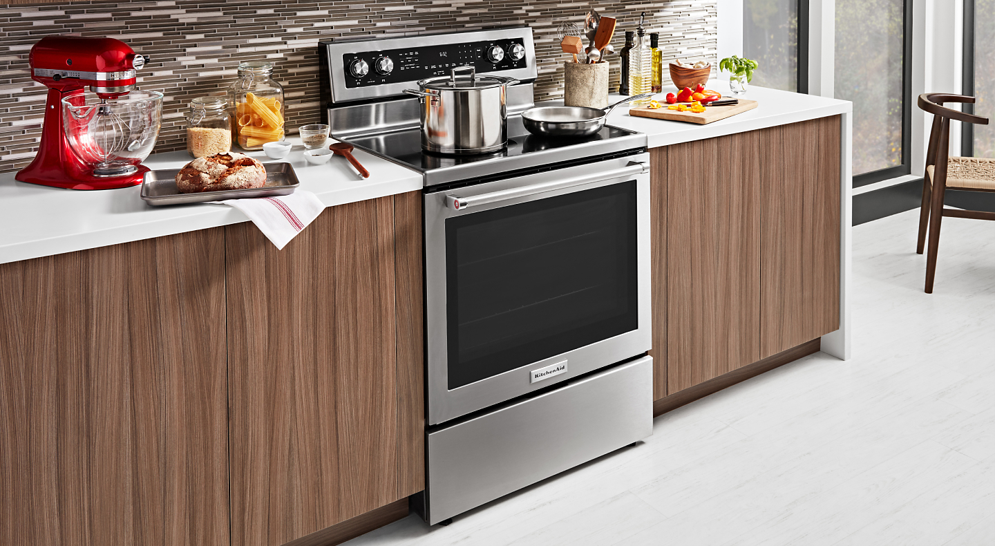 A stainless steel KitchenAid® slide-in range next to prepared dishes 