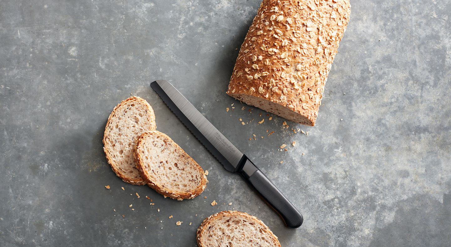 Half sliced loaf of bread on countertop with knife