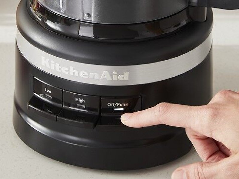 Hand pressing pulse button on a food processor