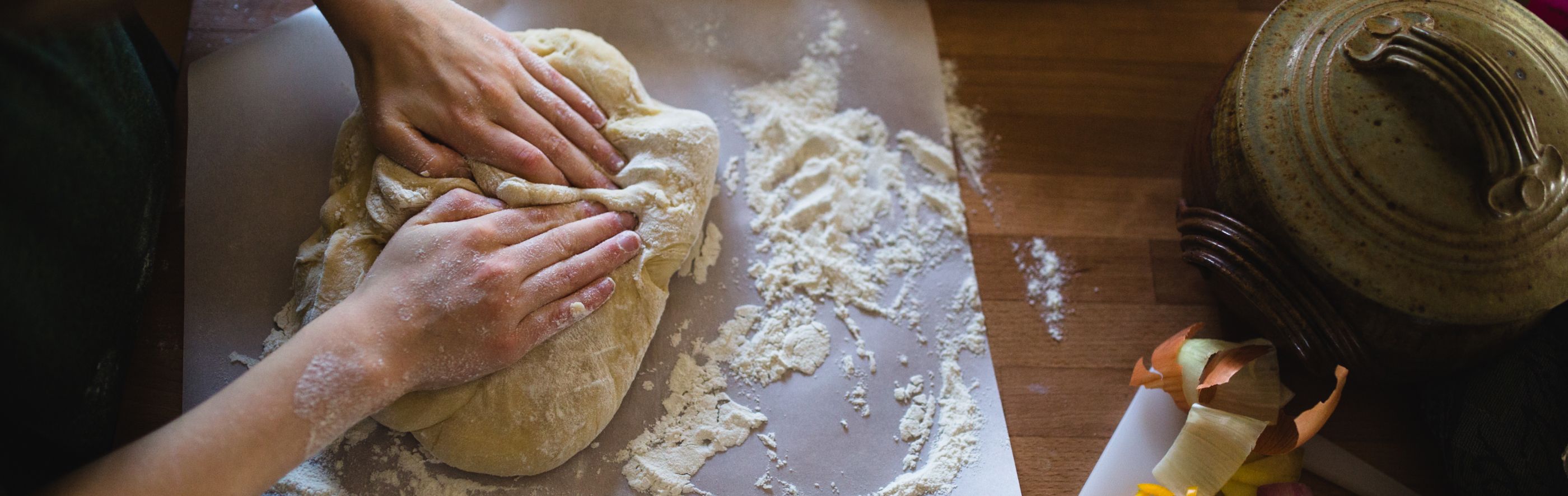 Top view of two hands kneading dough on countertop