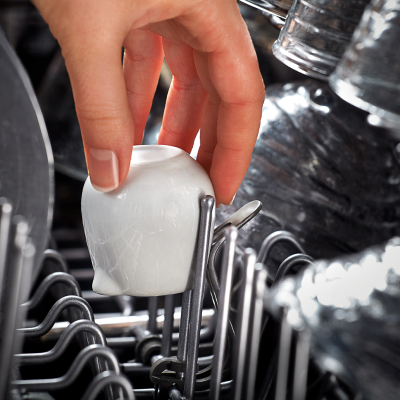 Person loading a small cup in a dishwasher