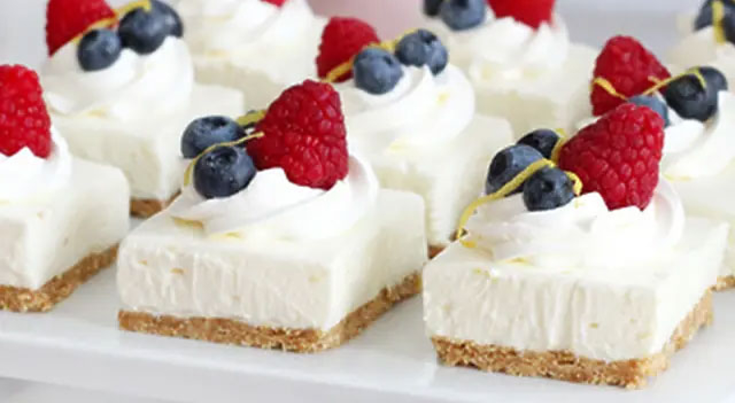 Cheesecake squares topped with whipped cream and fresh fruit