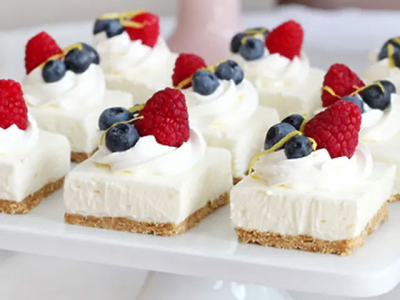 Cheesecake squares topped with whipped cream and fresh fruit