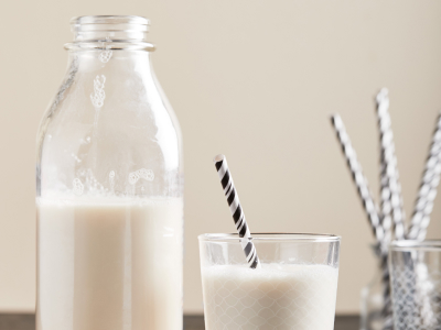 Glass bottle of milk next to glass of milk with gray and white striped straw