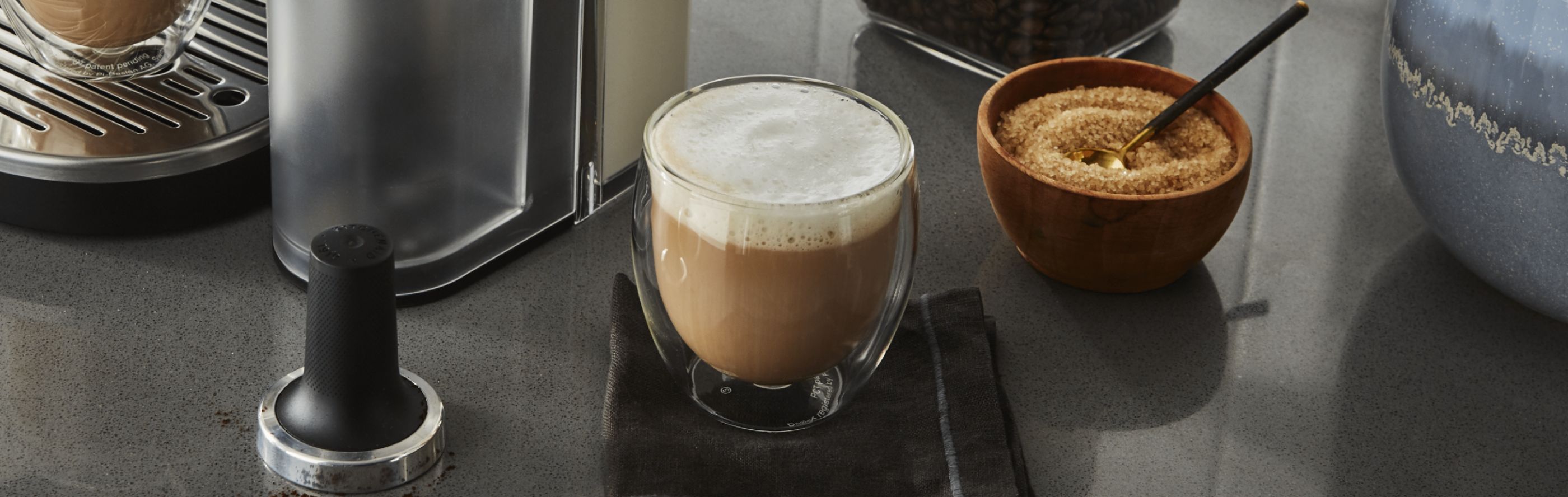 Espresso drink next to bowl of sugar