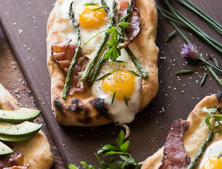 Brunch pizza topped with fried eggs and asparagus