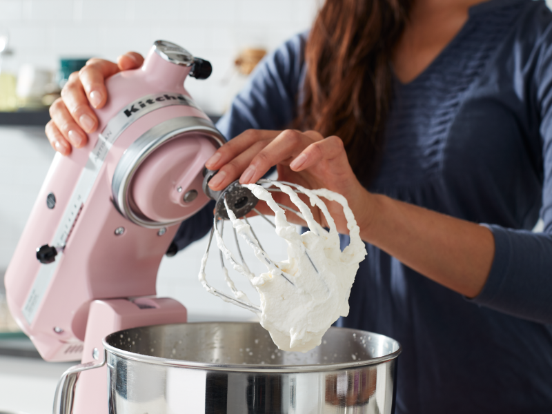 Person making whipped cream in a pink KitchenAid® stand mixer