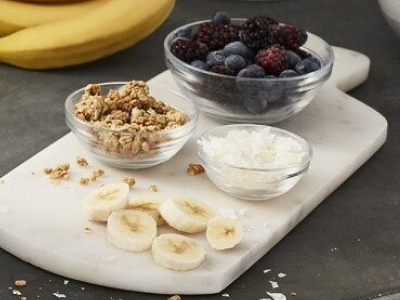 Berries, bananas and other mix-ins sitting on cutting board