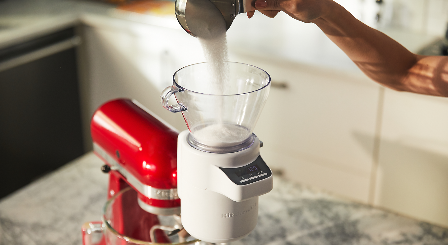 Person pouring ingredients into the KitchenAid® Sifter + Scale Attachment