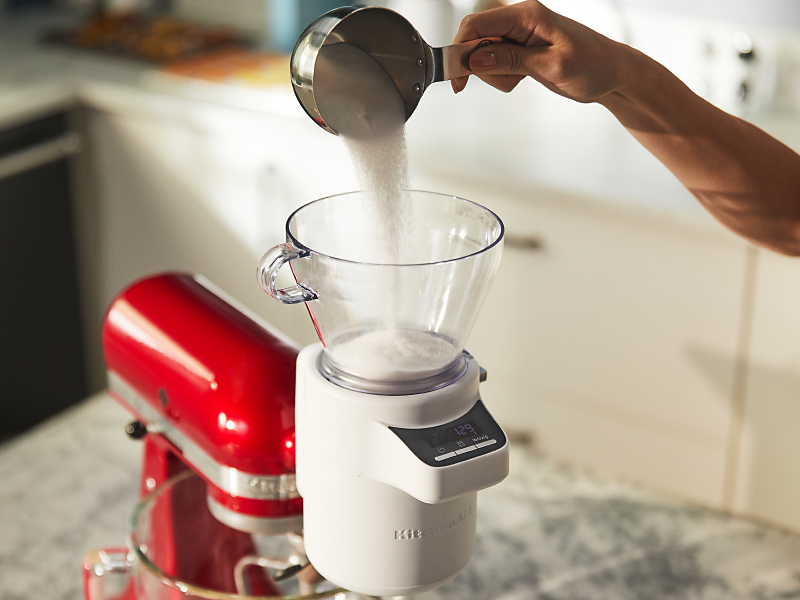 Person pouring ingredients into the KitchenAid® Sifter + Scale Attachment