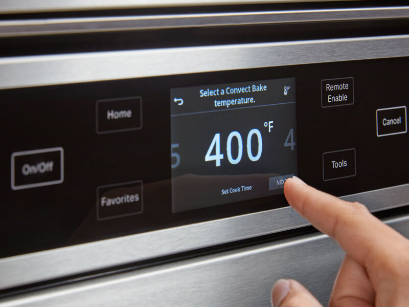 Person preheating the oven to 400°F on oven touchscreen