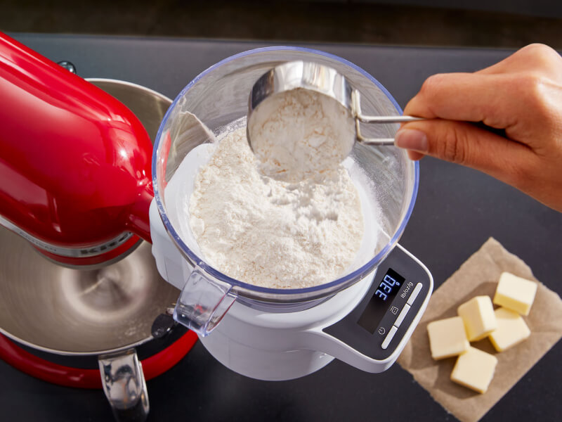 Person adding flour to the KitchenAid® Sifter + Scale Attachment