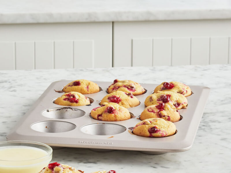 Partially empty muffin tin filled with baked cranberry muffins
