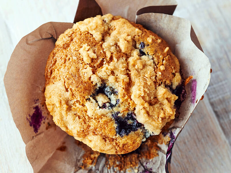 Birds-eye view of a streusel-topped blueberry muffin inside of a decorative liner