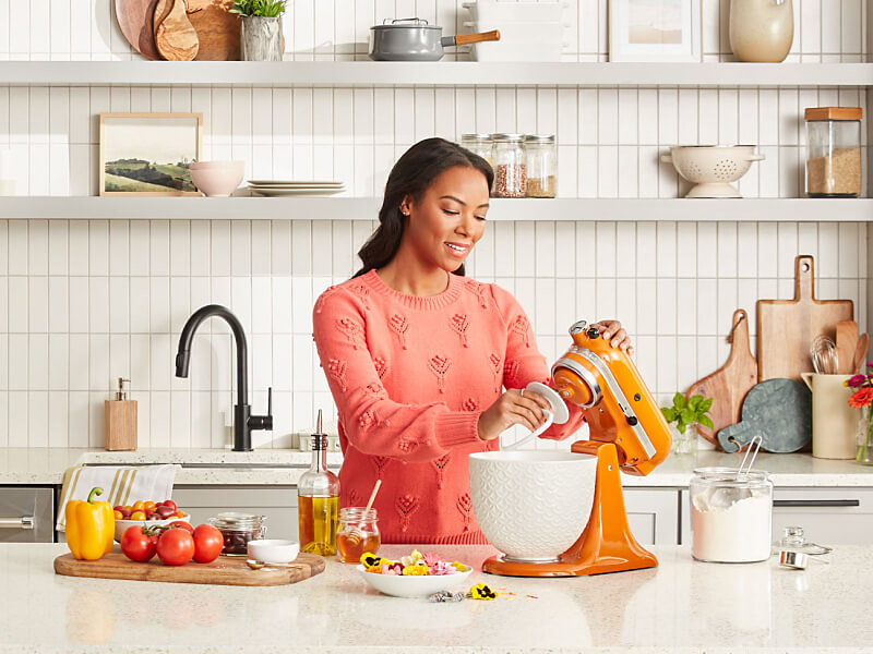 Person attaching the KitchenAid® Dough Hook accessory to an orange stand mixer