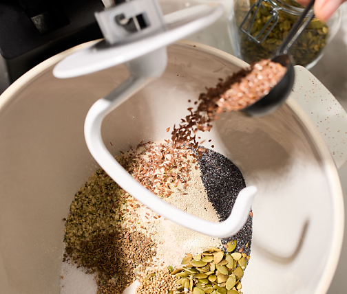 Person adding bread ingredients to stand mixer bowl