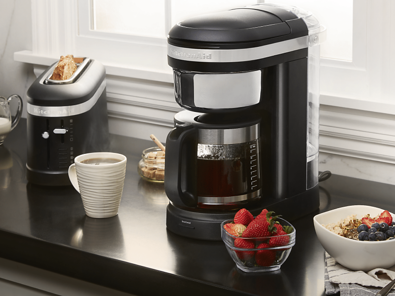 KitchenAid® coffee maker on countertop with coffee drink and breakfast foods