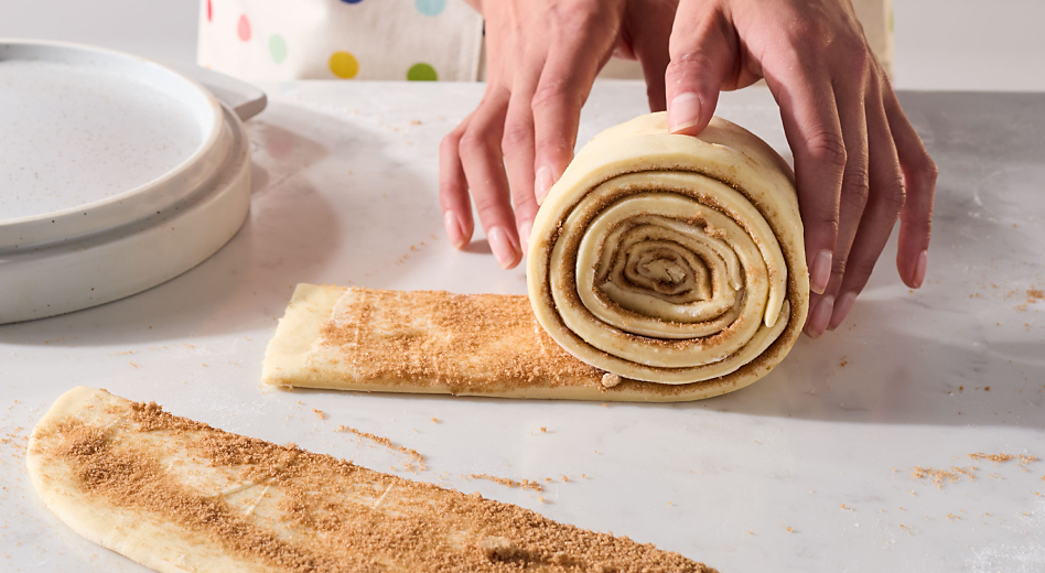Person rolling cinnamon roll bread dough 