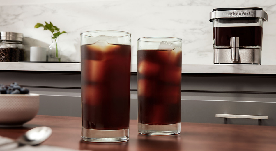 Two tall glasses of iced cold brew coffee on counter