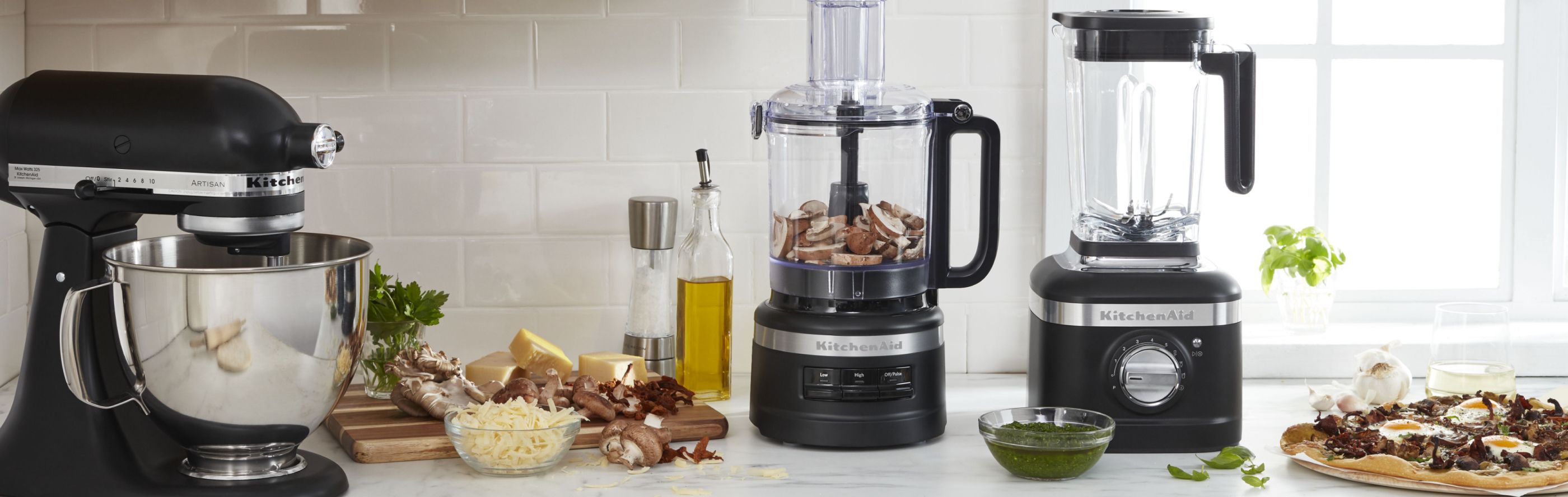Stand mixer, food processor and blender on kitchen counter with ingredients