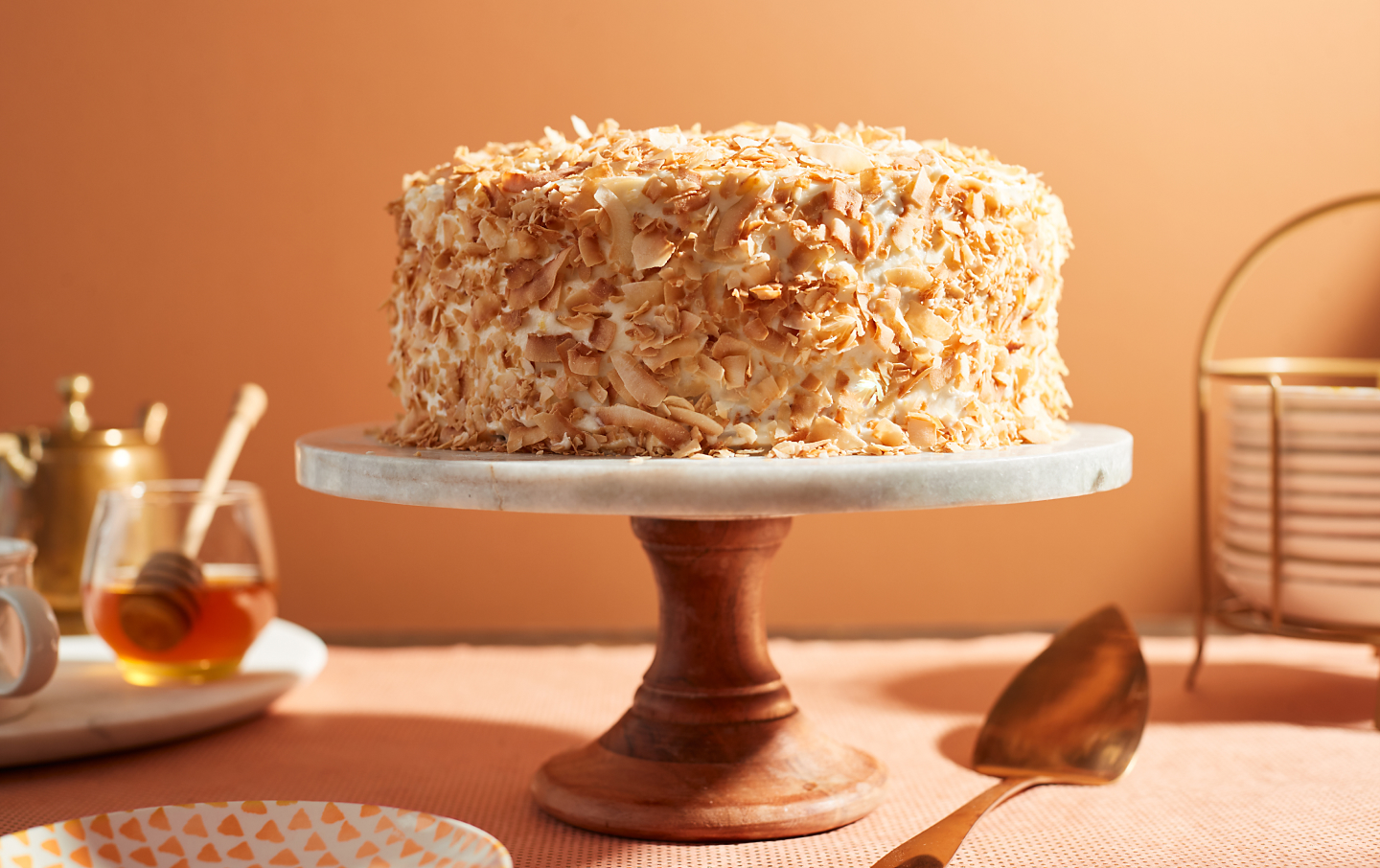 Cake covered in toasted coconut flakes on a cake stand