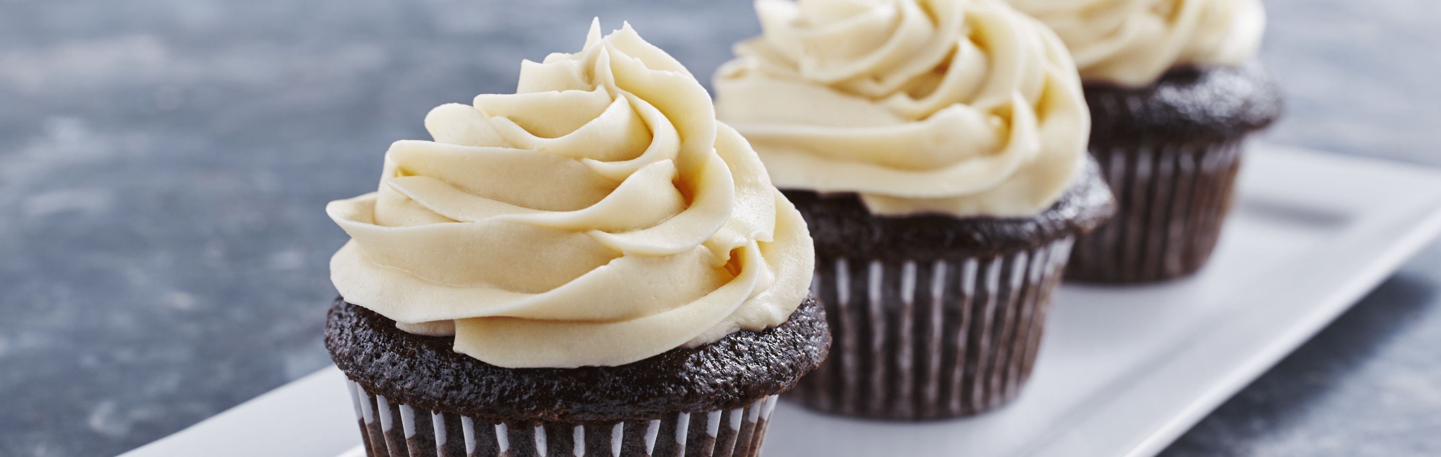 Three chocolate cupcakes topped with cream cheese frosting