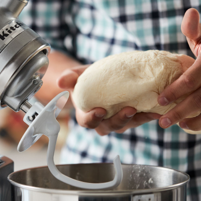Person removing dough from a stainless steel KitchenAid® stand mixer