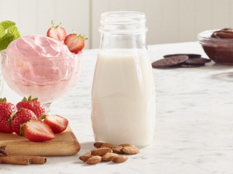 Strawberry ice cream next to a glass of milk.