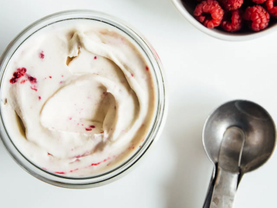 A dish of raspberry ripple nice cream next to an ice cream scooper