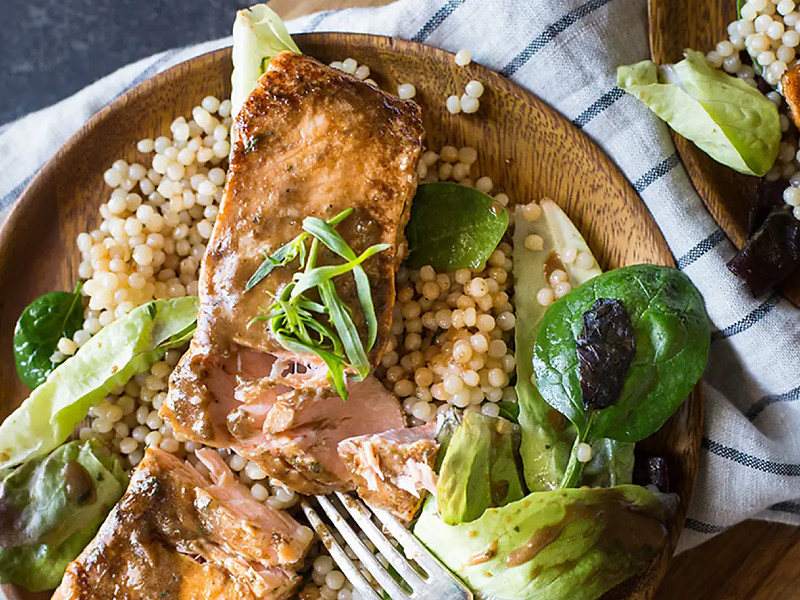 Salmon, couscous and greens on dinner plate