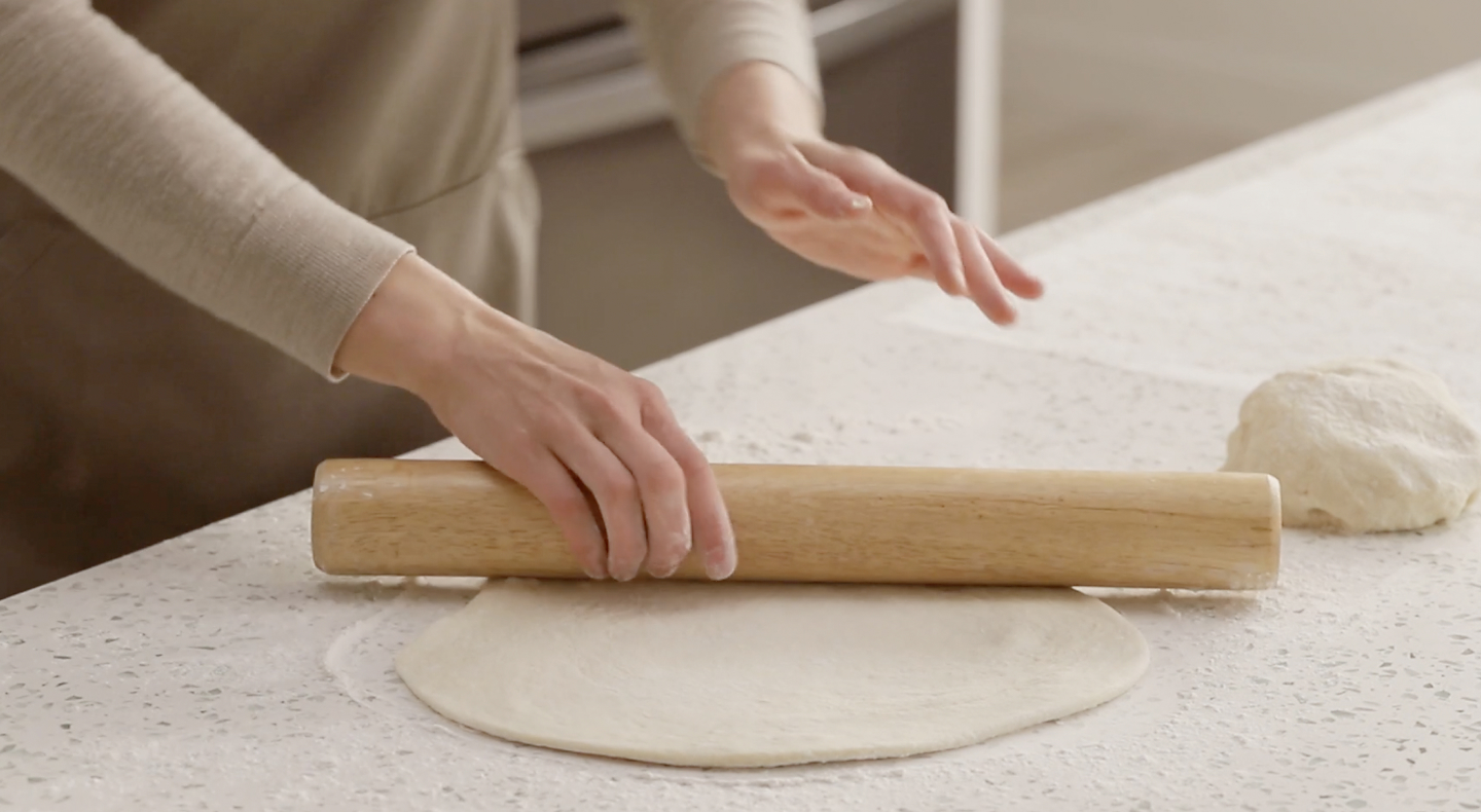 Person rolling out dough with a rolling pin