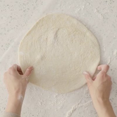 Homemade pizza dough on a floured surface