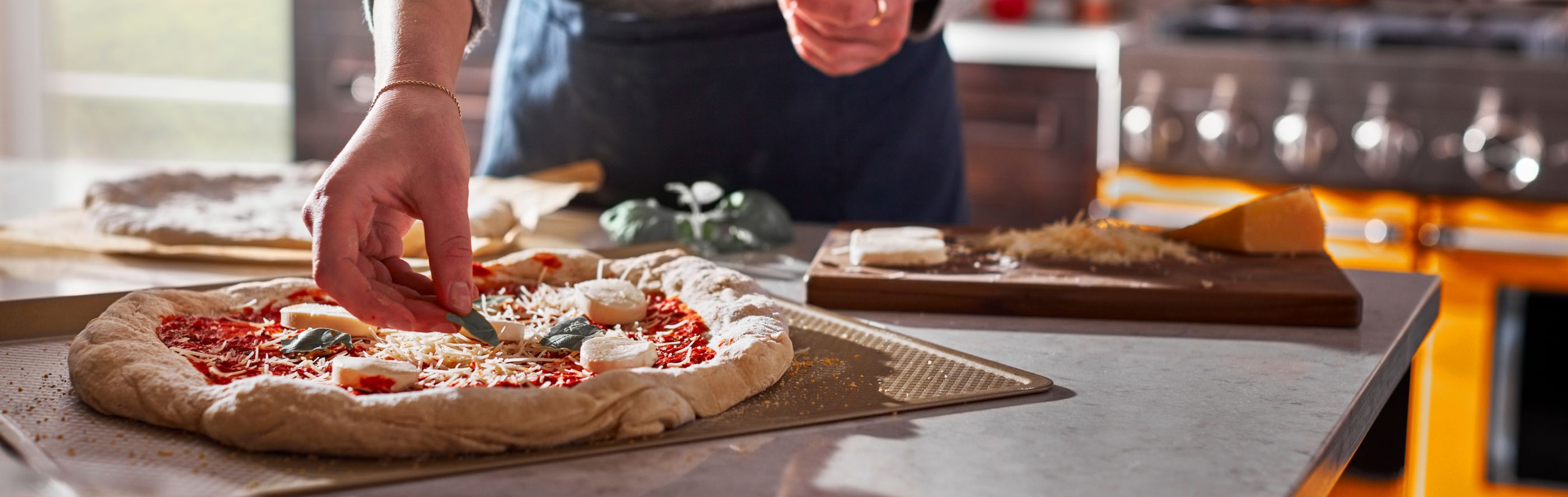 Person adding toppings to homemade pizza dough
