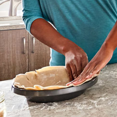 Maker shaping pastry dough into baking dish
