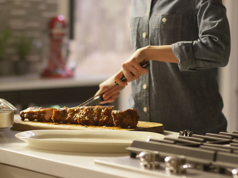 Cook cutting into a tender rack of ribs.