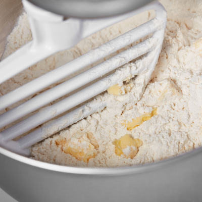 KitchenAid® pastry beater cutting butter into flour in bowl of KitchenAid® stand mixer
