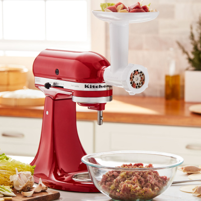 KitchenAid® stand mixer with meat grinder attachment grinding meat into bowl
