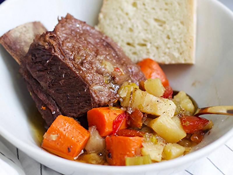 Short ribs with vegetables on plate with bread