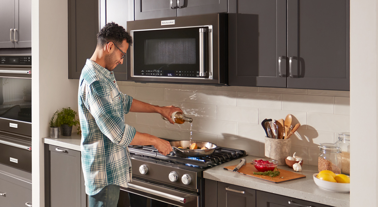 Person cooking on a KitchenAid® gas range