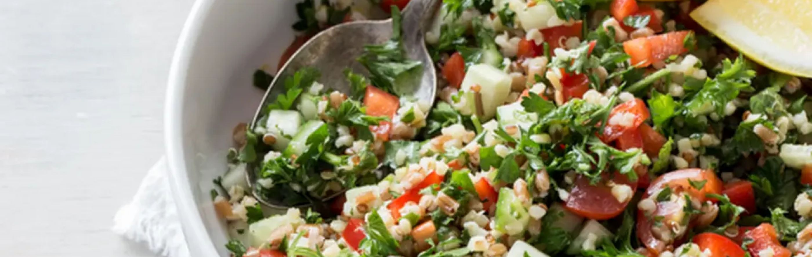A bowl of refreshing tabouli and a serving spoon.