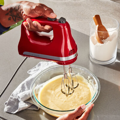 A person using a red KitchenAid® to whip cream