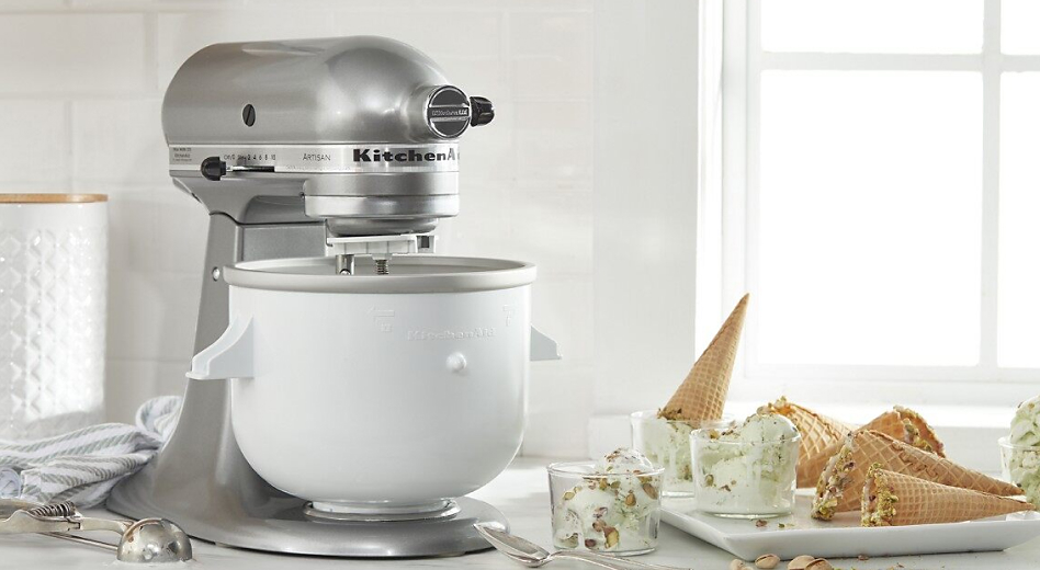 A KitchenAid® stand mixer with Ice Cream Maker attachment beside a tray of ice cream cones