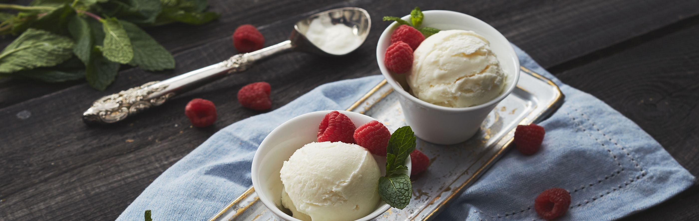 Individual bowls with scoops of vanilla ice cream and fresh raspberries on a table