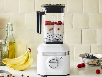 White KitchenAid® blender filled with milk and fruit on countertop