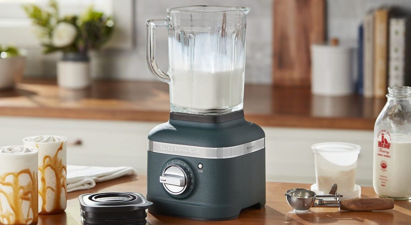 Black KitchenAid® blender filled with milk on countertop with top removed