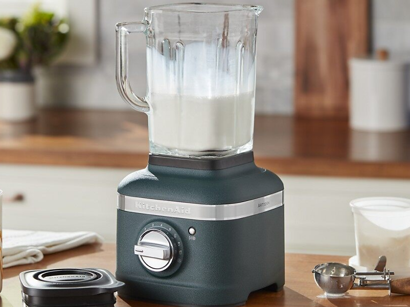 Black KitchenAid® blender filled with milk on countertop with top removed