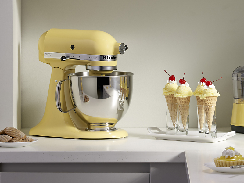 A yellow KitchenAid® stand mixer next to ice cream in waffle cones