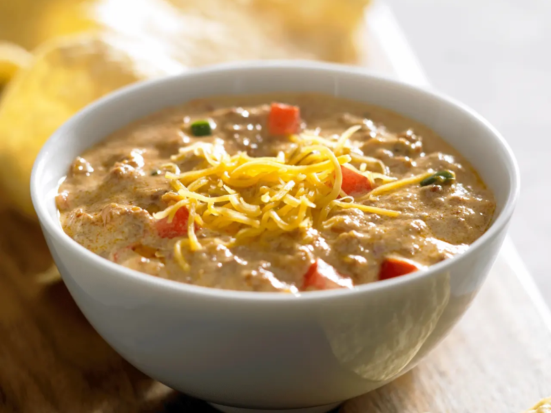 A bowl of homemade queso with shredded cheese sprinkled on top.
